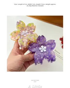 Dettaglio di grandi mollette per capelli a fiore di ciliegio in acetato con strass