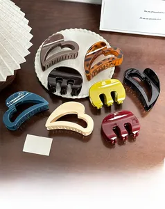 Detailed overhead shot of heart-shaped and three-prong hair claws in assorted matte colors