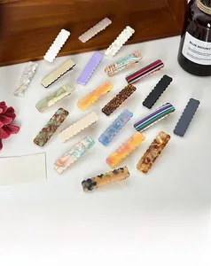 Vue détaillée des barrettes en acétate à bords ondulés aux motifs marbrés et tons unis
