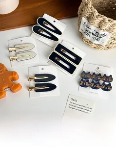 Flat lay of acetate hair clips in navy and beige with geometric and cat-shaped designs
