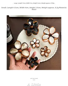 Detail of floral hair claws in black, white, and champagne resin on a classic wooden desk