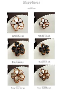 Detail view of flower hair clips in pearl white, black, and gold colors with 2 sizes