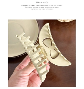 Close-up of matte cream-beige acetate hair claw clip showing sturdy teeth and metal spring
