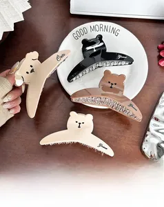 Detailed view of cute bear hair claws in beige and coffee colors on a wooden table