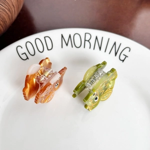 Cute cartoon owl acetate hair claws in orange and green marble texture on a white plate