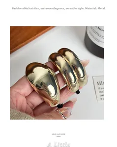 Close-up of a glossy gold metal ponytail holder with elastic hair rope held by hand