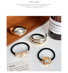 Detail of vintage metal hair ties with pearl accents on a minimalist white surface