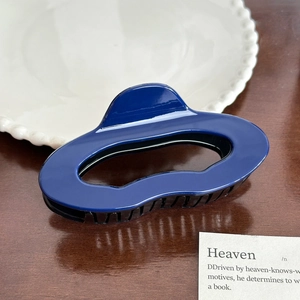 Detailansicht einer dunkelblauen, glänzenden Haarklammer aus Acryl auf einem Holztisch