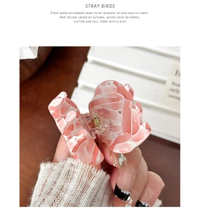 Detail of a pink marble-patterned acetate hair claw clip with delicate rhinestone accents
