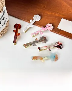 Detailed view of six acetate floral hair clips with elegant patterns and gold duckbill clips