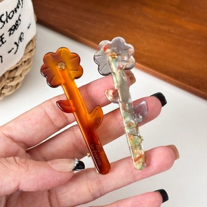 Floral acetate hair clips with rhinestone centers in amber and marble patterns
