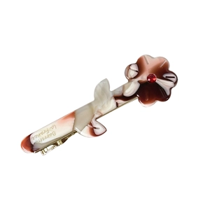 Vintage acetate flower hair clip with amber marble texture and a sparkling red rhinestone
