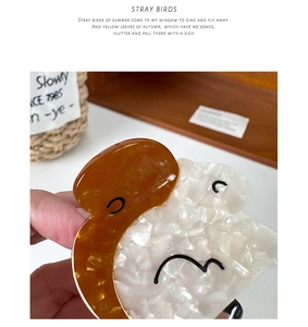 Detail of amber and pearl white acetate hair claw clip with minimalist face pattern