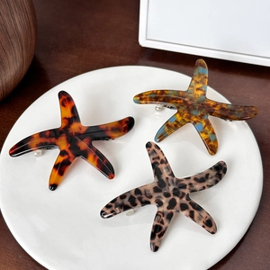 Starfish shaped acetate hair clips in tortoiseshell and marble patterns on white plate