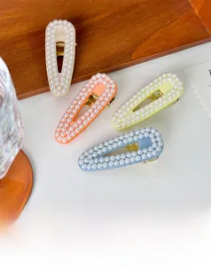 Detail view of four elegant pearl hair clips in beige orange yellow and blue colors