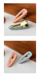 Close-up of pearl hair clips in orange and light blue with metal alligator grips