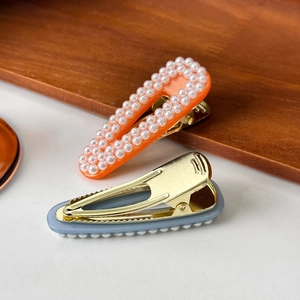 Elegant pearl hair clip set with orange acrylic base and gold duckbill clasp design