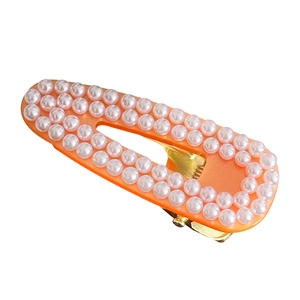 Elegant orange resin hair clip with rows of white pearls on a gold-tone metal base