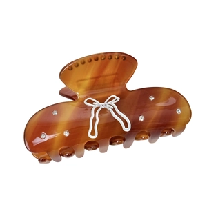 Brown amber patterned bow hair claw clip with rhinestones on a white background