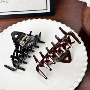 Classic black and amber acetate shark hair clips with gold metal spring on white plate