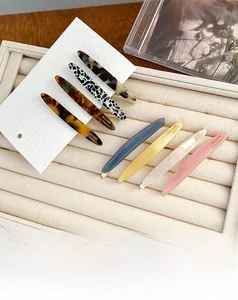 Close-up of acetate barrette hair clips in seven colors with elegant gold lettering
