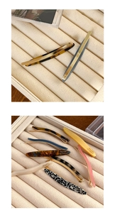Detailed view of assorted acetate hair barrettes with gold labels on a jewelry tray