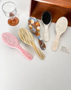 Detail van vijf acetaat haaborstels met marmeren en amberen texturen op houten blad