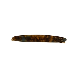 Minimalist tortoiseshell acetate hair barrette with gold logo on a white background