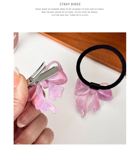 Close-up of pink marble pattern acetate bow hair clip and elastic scrunchie set