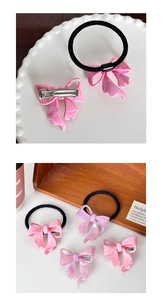 Detailed close-up of pink acetate marble bow hair tie and metallic duckbill hair clip set