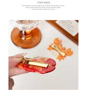 Detail of red lobster and orange crab hair clips with marble texture and gold duckbill clip