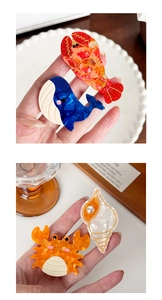 Close-up of ocean-themed acetate hair clips featuring lobster, whale, crab and shell motifs