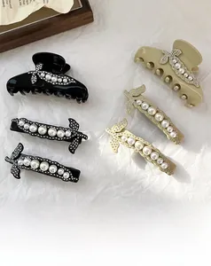 Dettagli di fermagli per capelli con perle e strass nei colori nero, crema e dorato
