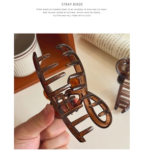 Détail d'une pince à cheveux en résine marron translucide avec un design brillant en huit