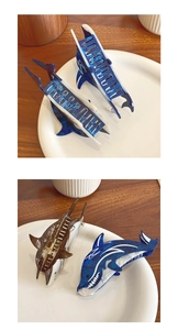 Dettaglio di pinze per capelli in acetato a forma di squalo, texture marmorizzata blu e marrone