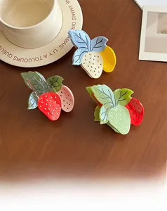 Trois pinces à cheveux fraises colorées en rouge, jaune et vert sur table en bois