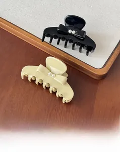 Détail de pinces à cheveux élégantes en acétate avec nœud et perles en crème et noir