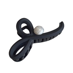 Pince à cheveux noire mate avec perle marbrée pour coiffure élégante sur fond blanc