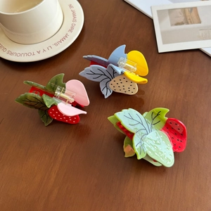 Trois pinces à cheveux en acétate en forme de fraise sur un fond de bois rustique