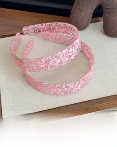 Gros plan du motif floral rose sur le serre-tête large en acétate au fini courbé