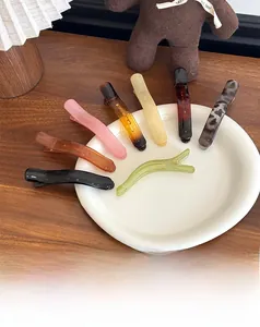 Set of 8 resin duckbill hair clips in assorted colors on a white ceramic plate