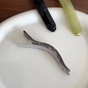 Translucent jelly duckbill hair clips in grey, black, and green on a ceramic plate