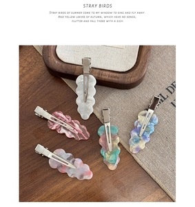 Close-up of acetic acid marble hair clips with silver metal duckbill clips on wooden tray