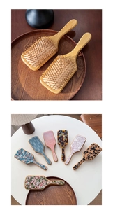 Detailed view of acetate airbag massage brush with wooden handle and floral patterns