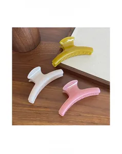 Dettaglio di pinze per capelli in resina nei toni giallo zenzero, bianco crema e rosa ciliegio