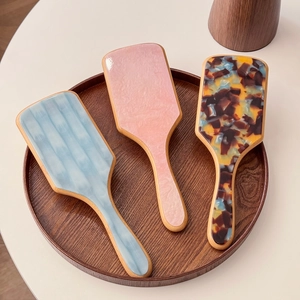 Acetate hair brushes with marble patterns and natural wood handles in a round tray