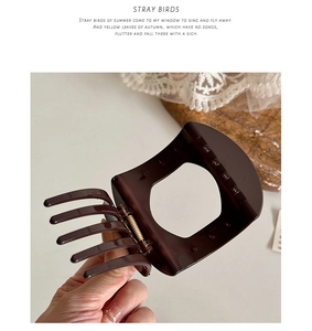 Detail view of large dark brown hair claw clip with strong gold metal spring mechanism
