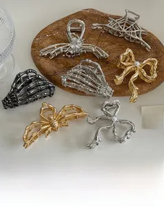 Detailed view of gothic Y2K silver spider web and skull hand hair clips with pearls