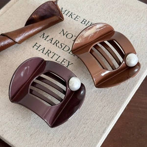 Elegant set of two brown hair claw clips with pearl detail on a warm vintage background