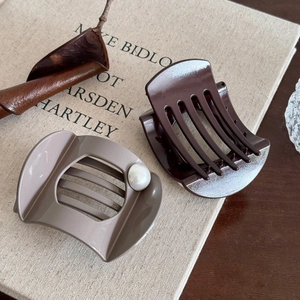 Vintage large pearl hair claws in taupe and dark coffee colors on a minimalist book cover
